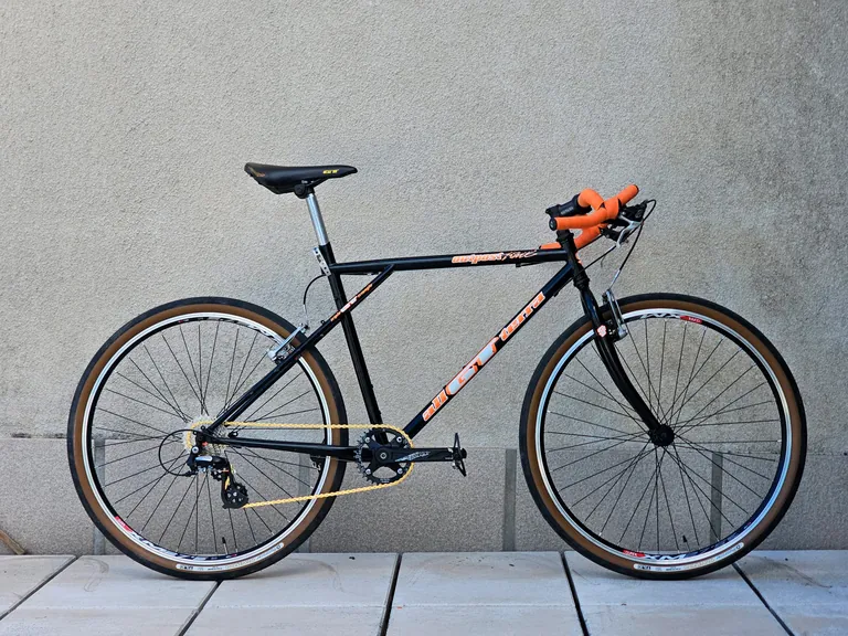 GT Al Terra outpost preta e laranja convertida de 26" para 650b com guiador de gravel.